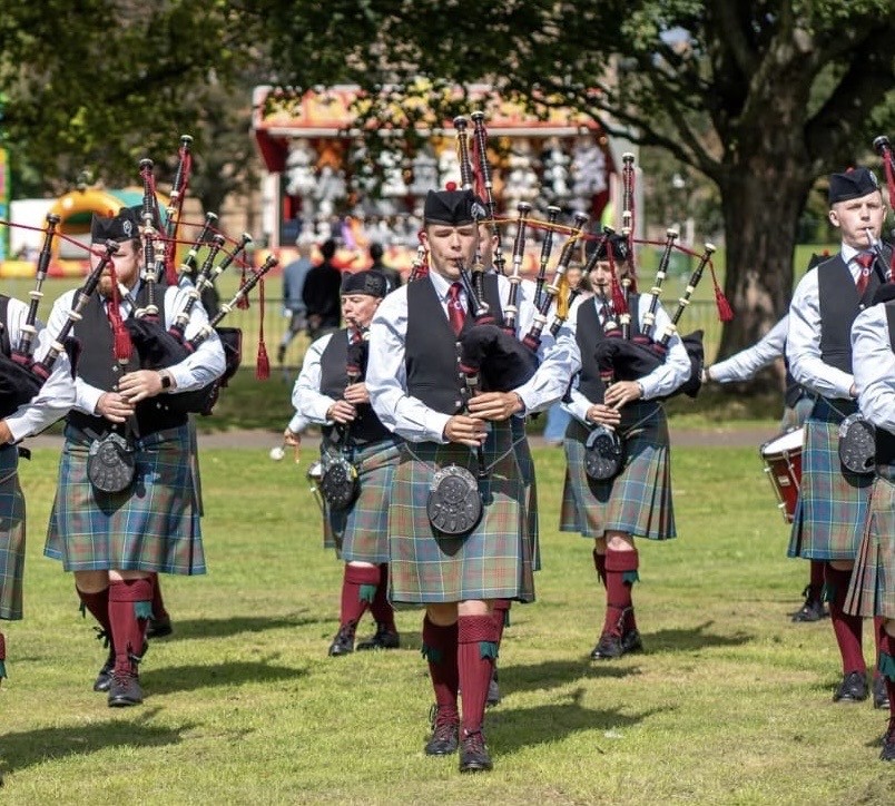 Pipe band marching outdoors in sunlight